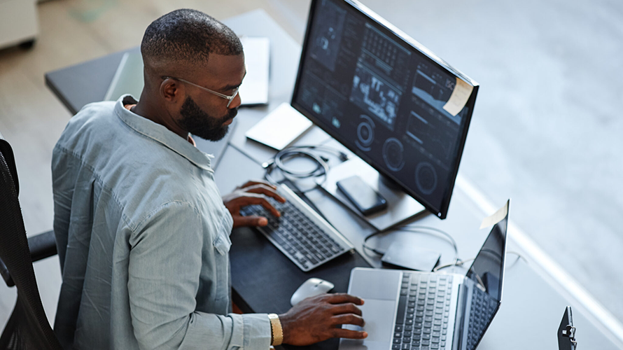 Young businessman working on a computer with charts and diagrams on the screen.