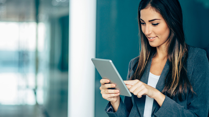 Young businesswoman standing in hallway with a computer tablet.