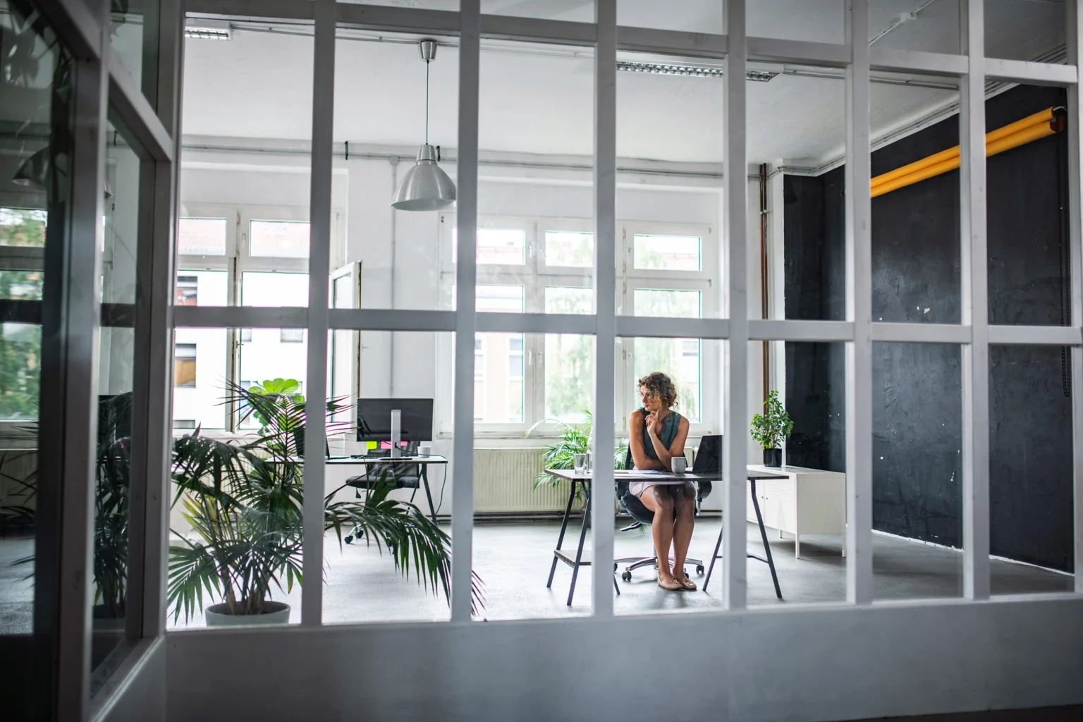 Woman at a desk in a room surrounded by white-framed windows.